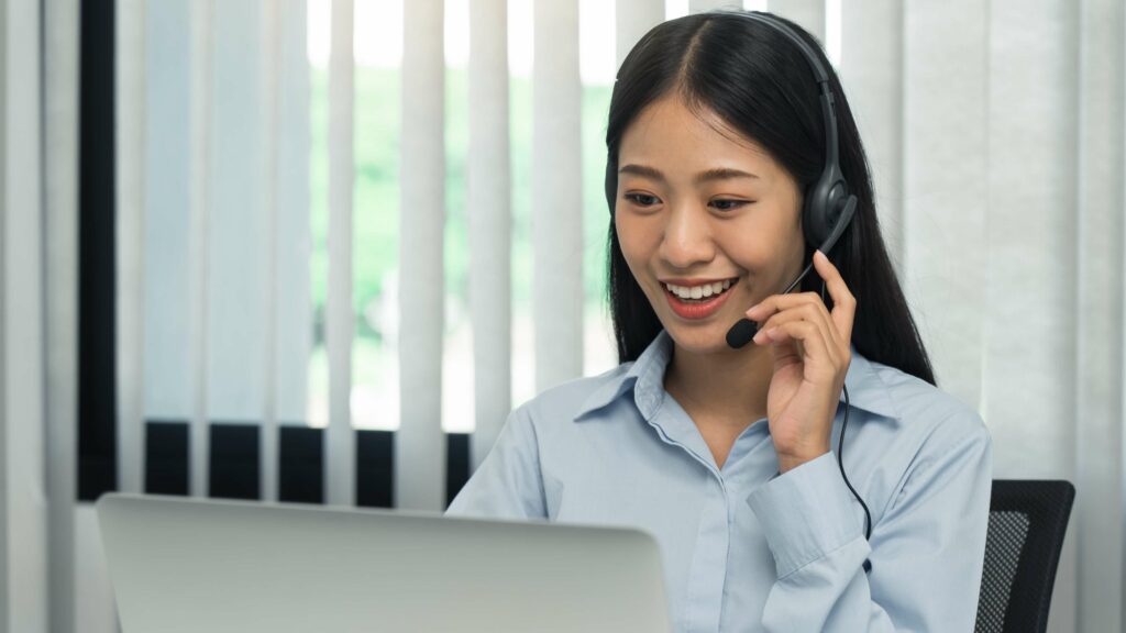 a woman wearing a headset and looking at a laptop