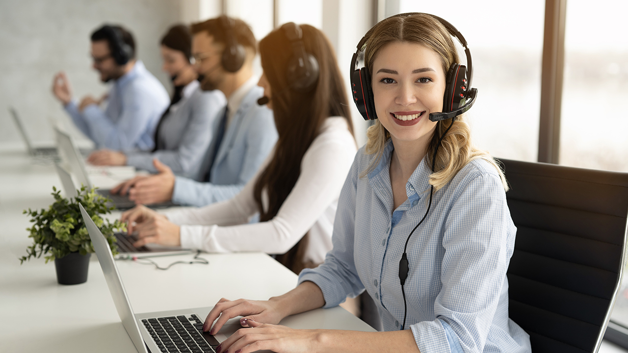 Smiling female BPO agent with headset providing customer support in a modern contact center, representing outcome-focused next-gen BPO services.