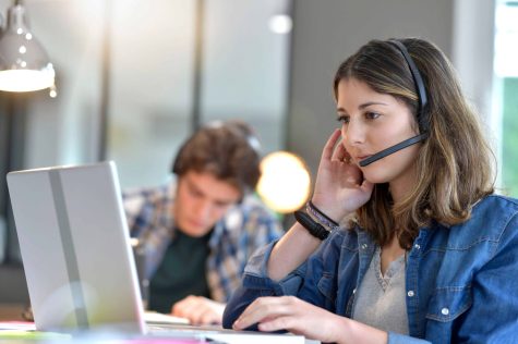 a woman wearing a headset and looking at a laptop