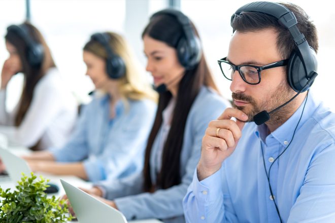 Focused BPO team in a modern contact center using headsets and laptops—illustrating outsourcing challenges and scalable solutions