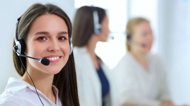 Smiling businesswoman or helpline operator with headset and computer at office