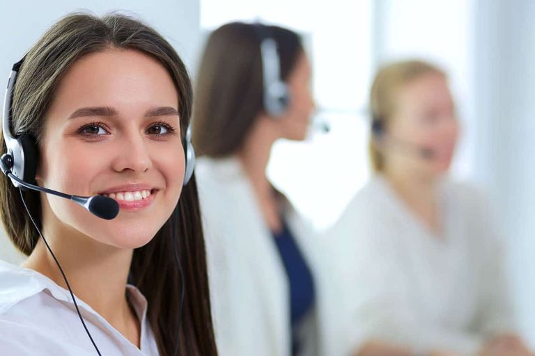 Smiling businesswoman or helpline operator with headset and computer at office