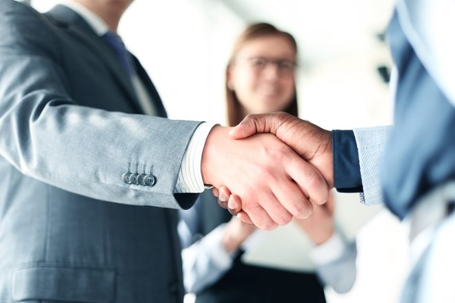 Close-up of business professionals shaking hands in office setting, symbolizing trust, partnership, and renewed collaboration in BPO-client relationships.