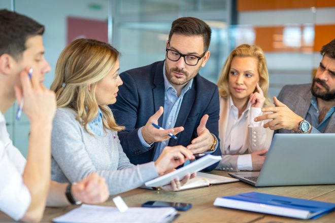 Diverse business team in a modern office engaged in a strategic discussion, representing collaborative leadership and innovative thinking in customer experience outsourcing.