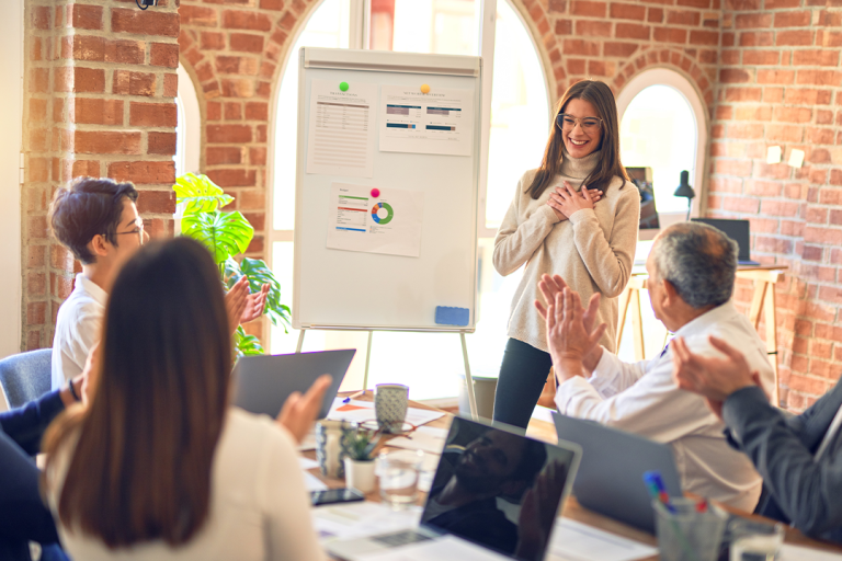 Team applauding a presenter in a modern office, discussing omnichannel retail strategies and customer experience improvements using data and analytics on a whiteboard.